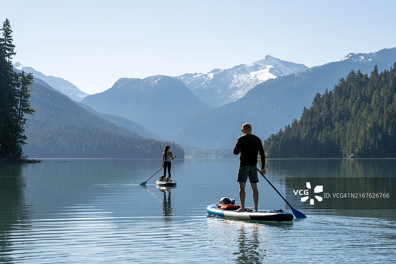 情侣在惠斯勒的山区湖泊上划桨图片素材