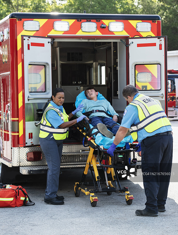 急救人员将少年抬上担架送入救护车图片素材