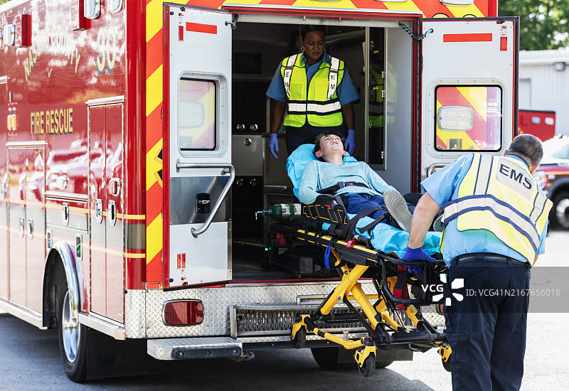急救人员将少年抬上担架送入救护车图片素材