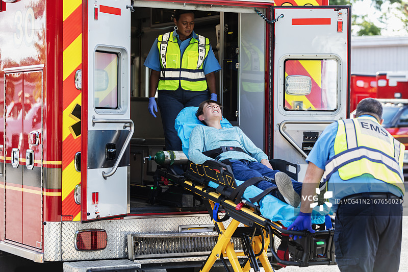急救人员将少年抬上担架送入救护车图片素材