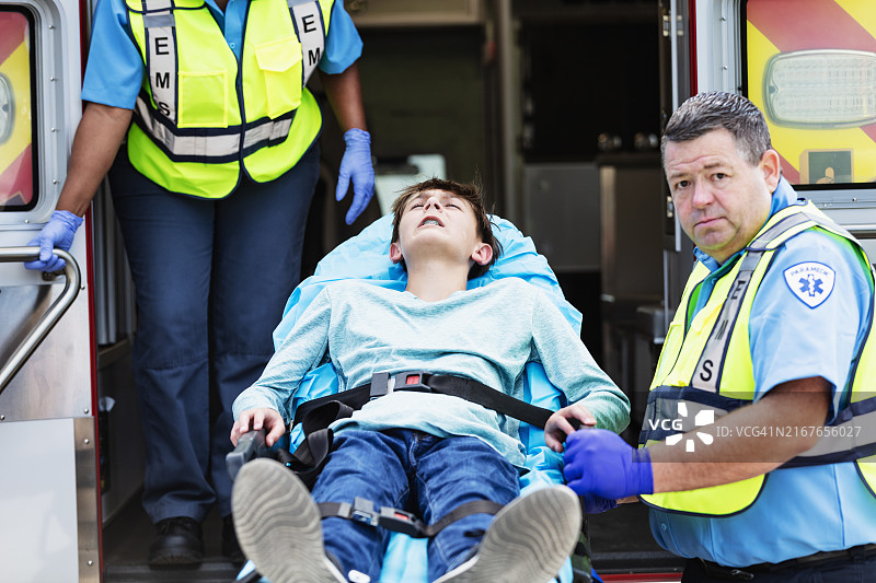 急救人员将少年抬上担架送入救护车图片素材