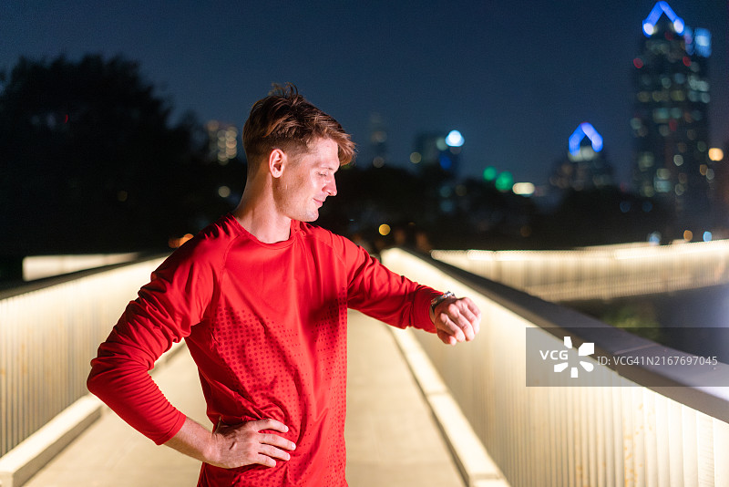 男人在夜晚查看智能手表上的健身数据图片素材