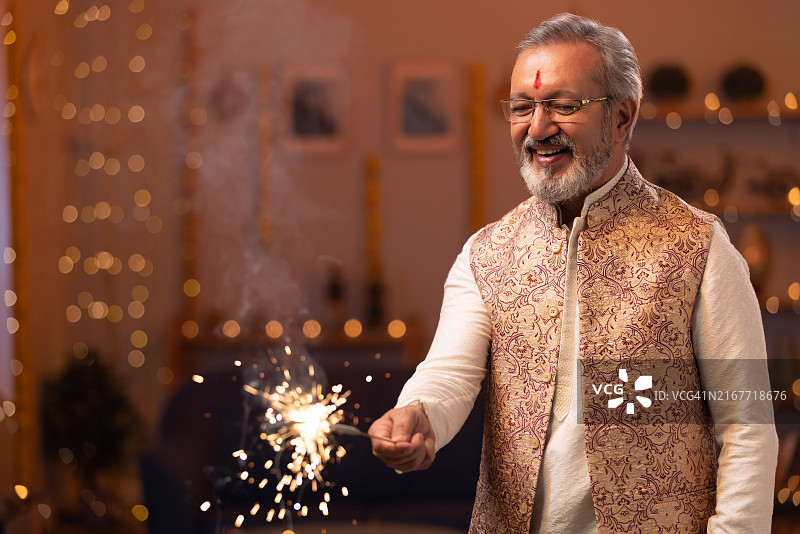 年长的男人在排灯节期间在家燃放烟花棒图片素材
