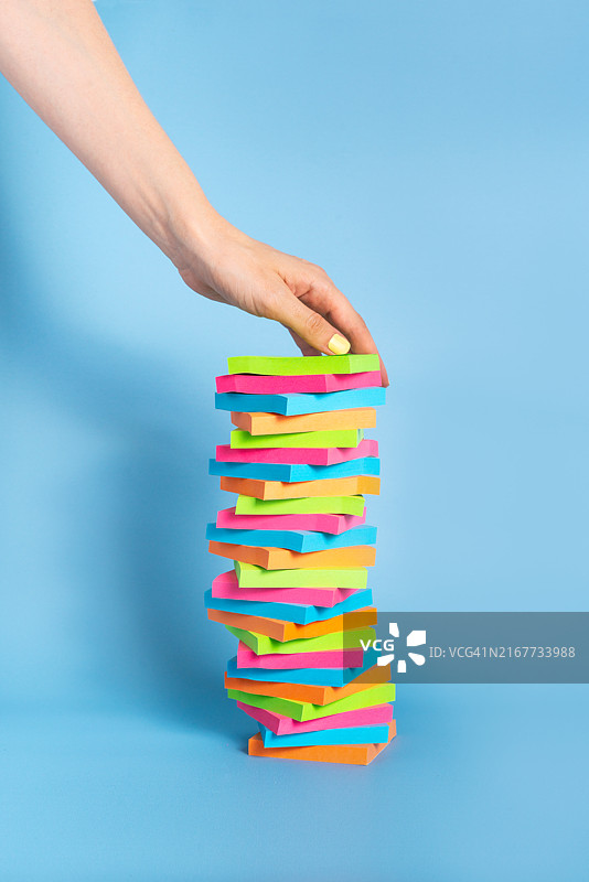 蓝色背景上的一摞便利贴，手从顶部取下一张图片素材