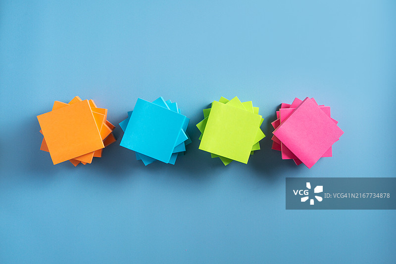 蓝色背景上整齐堆叠的彩色便签纸图片素材