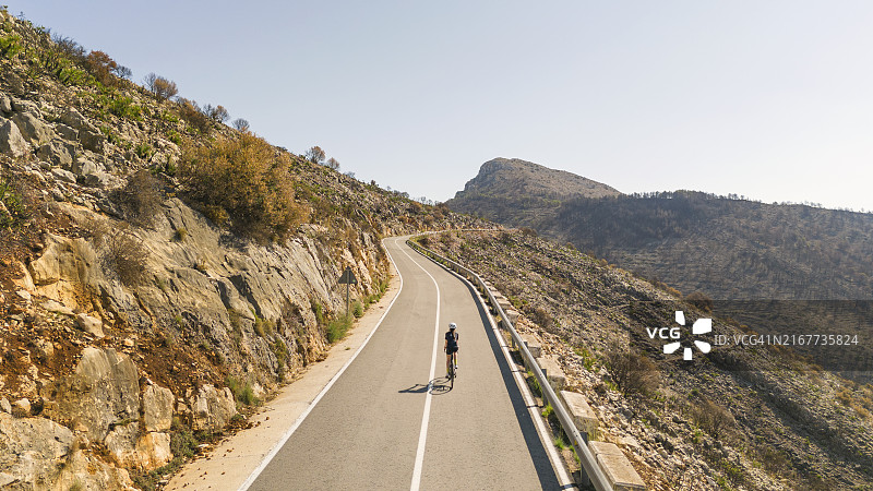 西班牙山区，少女骑公路自行车的后方航拍图片素材