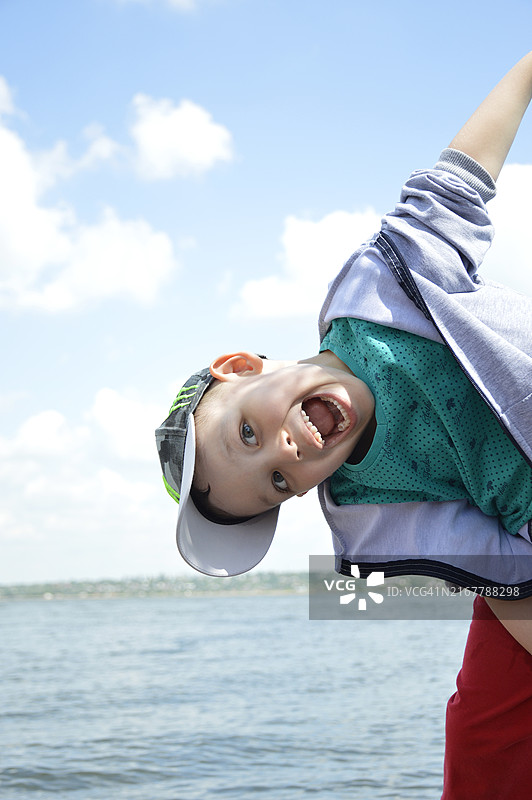 戴帽子的男孩，背景是水和蓝天白云图片素材