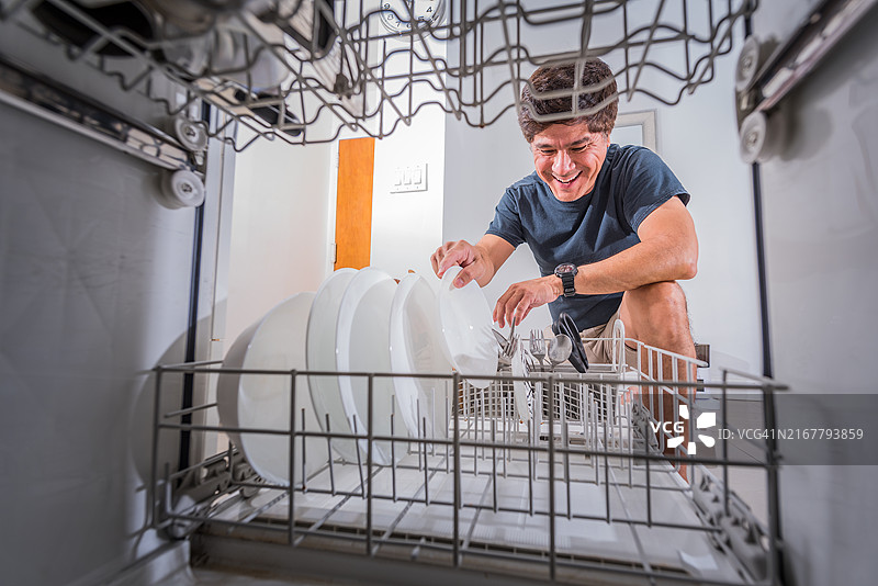 亚洲男子微笑着在装载洗碗机图片素材