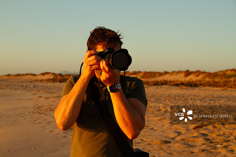 年轻男人在莱斯德韦塞斯海滩拍摄黄金时段图片素材