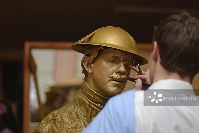 化妆师在表演前给演员脸上涂金漆图片素材