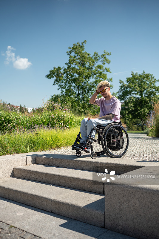坐在轮椅上试图下楼梯的激动男子图片素材