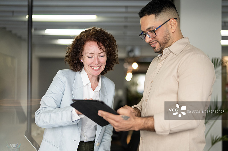 两位同事在数字平板电脑上查看数据时共享库存信息图片素材