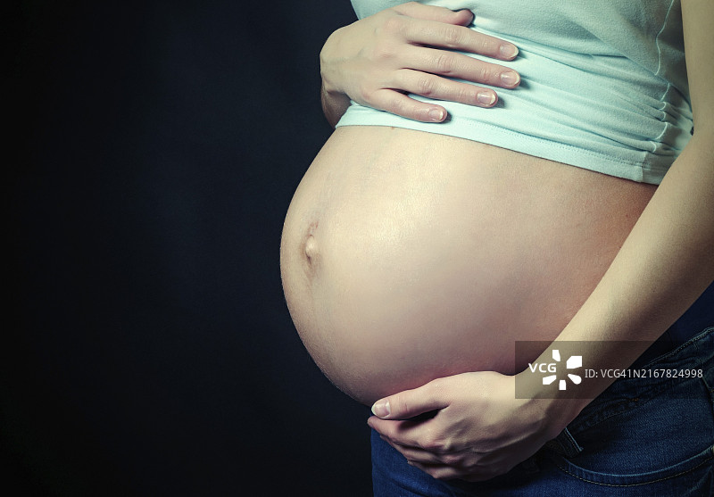 黑色背景下的孕妇腹部图片素材