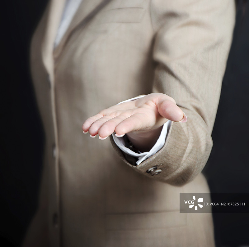 女性手在黑色背景上拿着、展示或给予某物图片素材