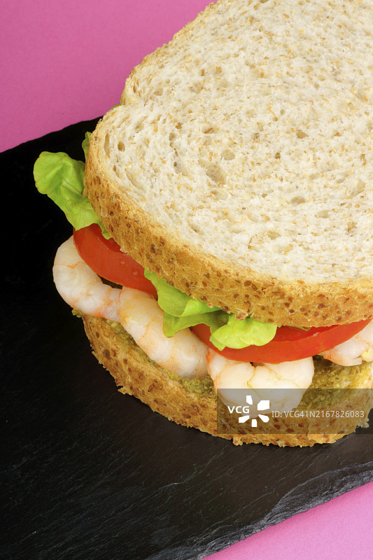 粉色背景石板托盘鲜虾三明治图片素材