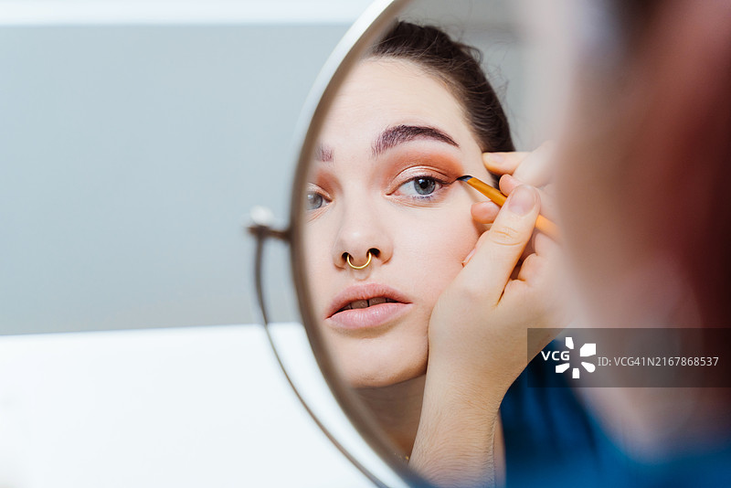 白人女性对着镜子画眼线的特写图片素材