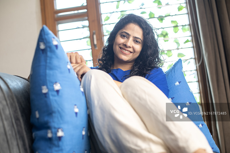 快乐美丽的女人在家里的沙发上沉思图片素材