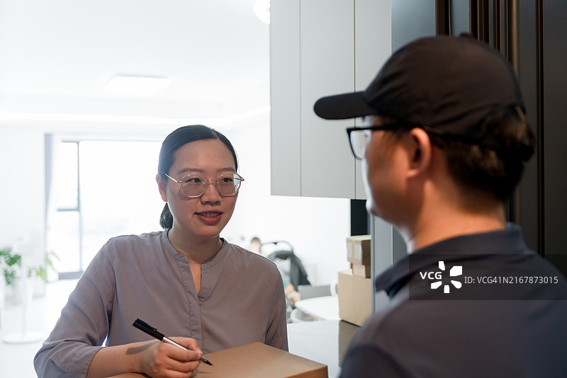 亚洲家庭在家中签收快递图片素材