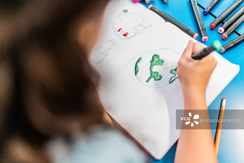 女学生在学校笔记本上画地球图片素材