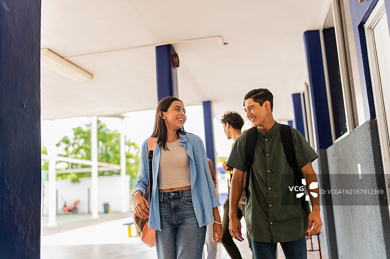 青少年学生在学校里边走边聊图片素材