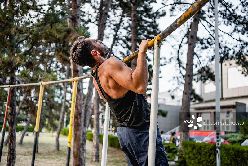 健身男士在户外单杠上做引体向上图片素材