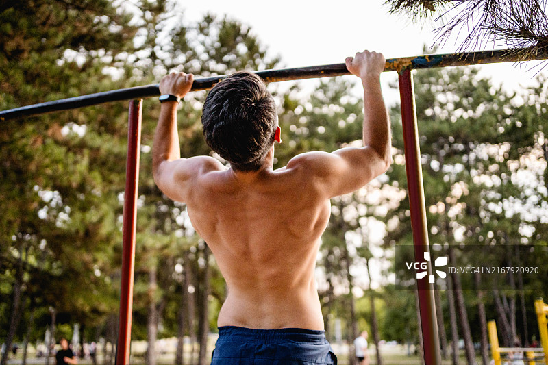 健身男士在户外单杠上做引体向上图片素材