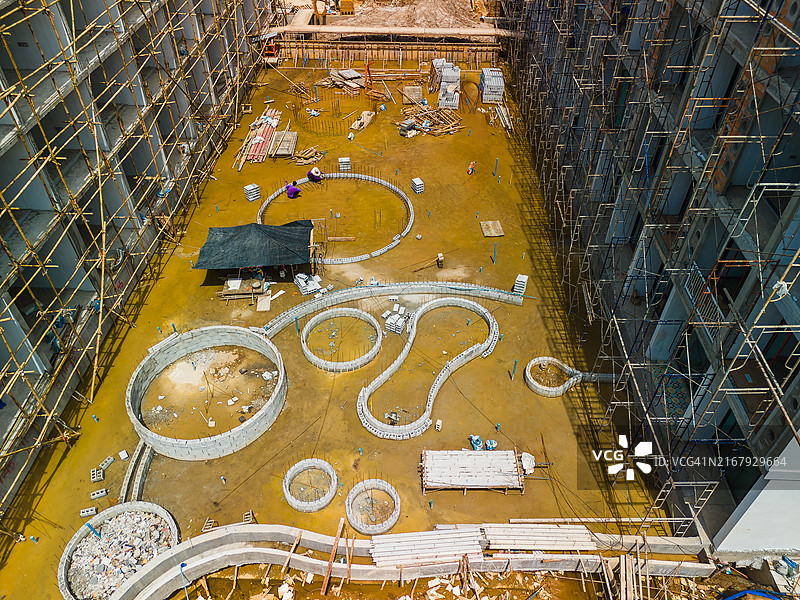 大型建筑工地鸟瞰图：脚手架、机械、起重机和挖掘机正在施工，许多工人正在协助施工图片素材