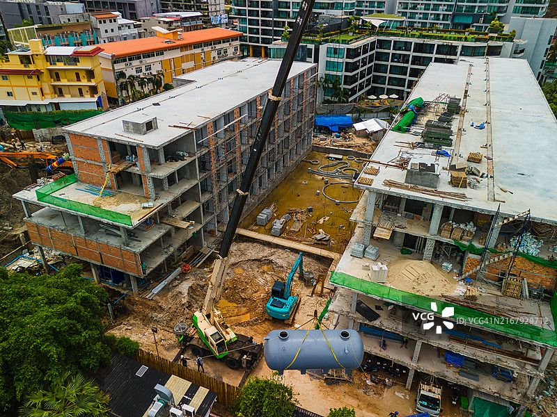 大型建筑工地鸟瞰：工人与起重机移动化粪池或水箱图片素材