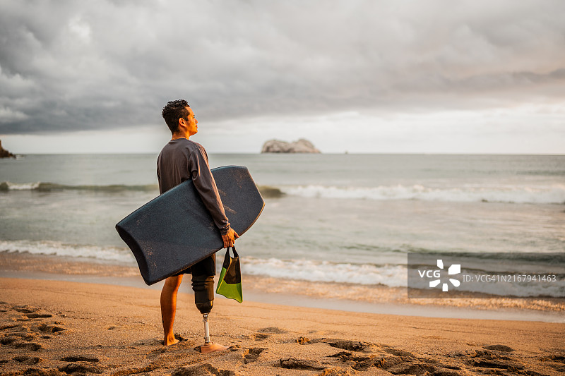 中年冲浪者在海滩上眺望远方图片素材