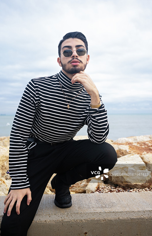 帅气留胡须的时尚男模特戴墨镜在户外摆姿势图片素材