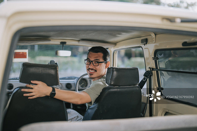 快乐的亚洲中国男人坐在SUV里周末早上回头看图片素材
