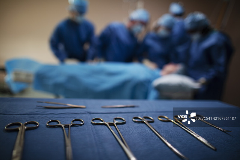 医院手术室内的手术器械托盘，背景是医疗团队和患者图片素材