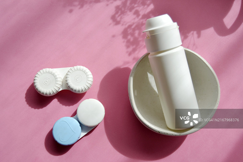 粉色背景上的隐形眼镜和生理盐水图片素材
