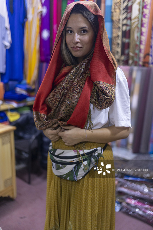 女人在街头市场试戴围巾的肖像照图片素材