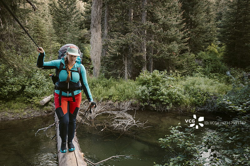 背包客在倒下的树上穿越卡尤什河图片素材