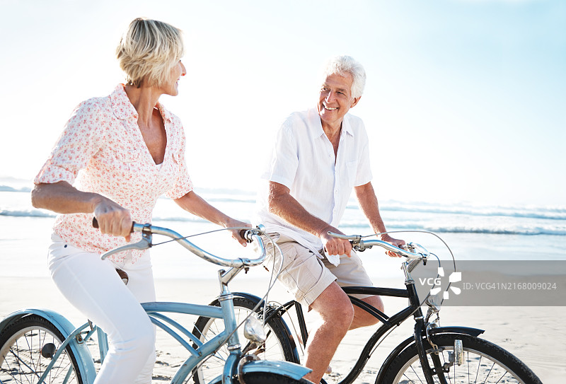 海滩上骑自行车的年长夫妇，享受生态友好型假期图片素材