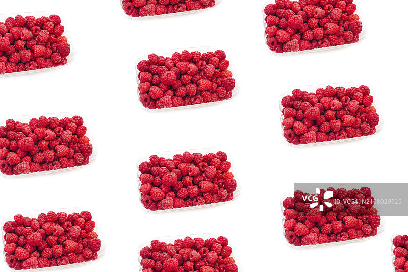 白色背景下装满新鲜红色覆盆子浆果的透明塑料容器图片素材