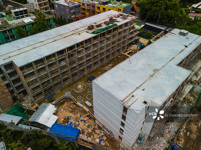 大型建筑工地鸟瞰图：脚手架、机械、起重机和挖掘机正在施工，许多工人正在协助施工图片素材