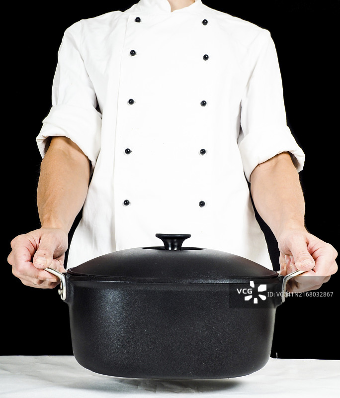 厨师手持砂锅，白色桌布黑色背景图片素材