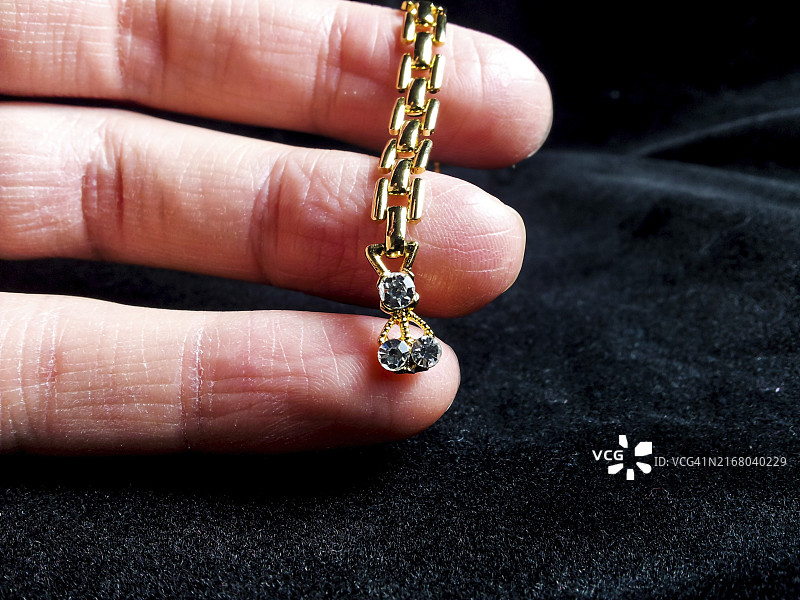 黑色背景上戴着钻石黄金戒指的手图片素材