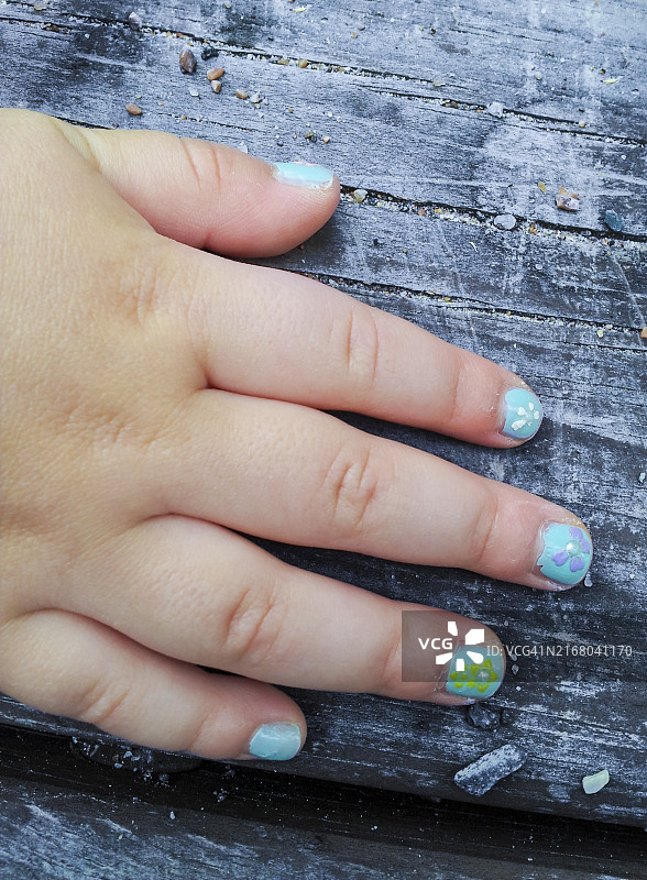 涂着花朵美甲的孩子，面向旧木头图片素材