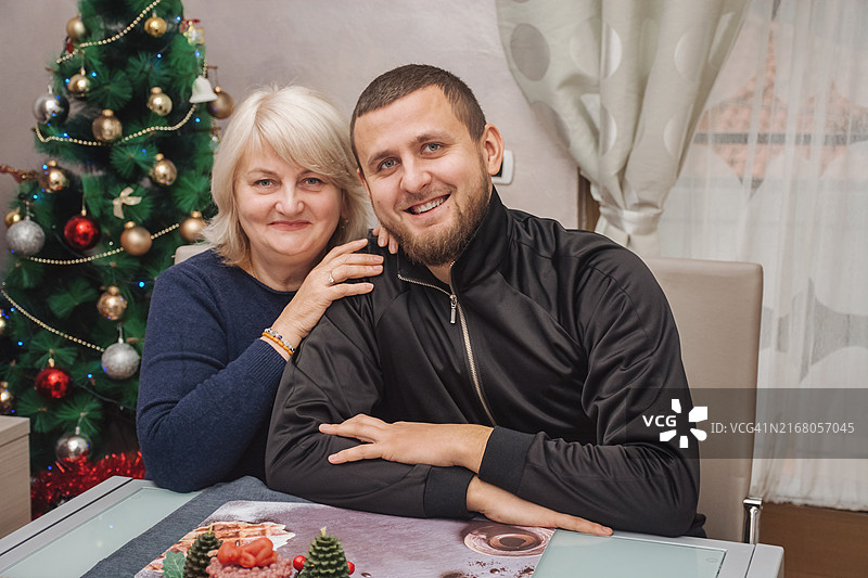 母子在圣诞树背景下拥抱微笑图片素材