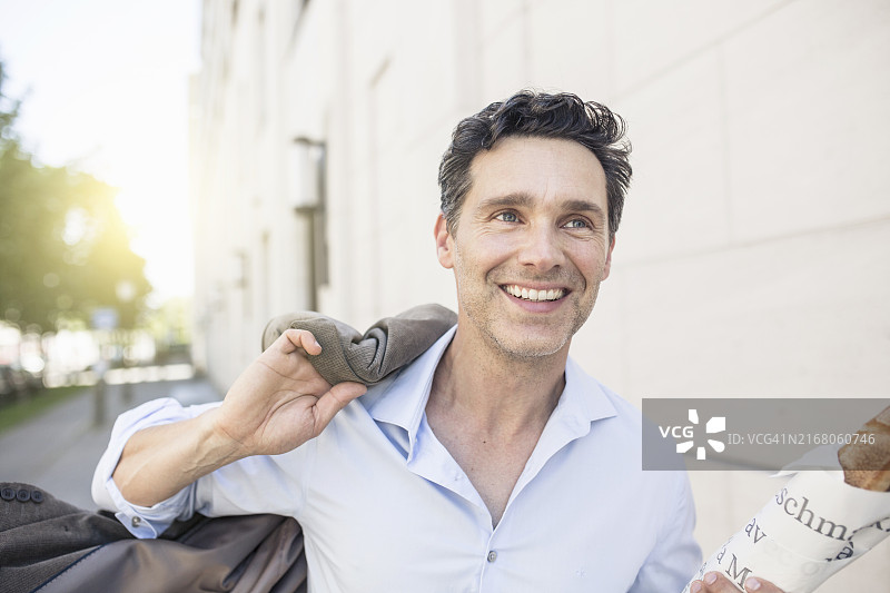 快乐的商人拿着法棍面包穿着西装奔跑图片素材