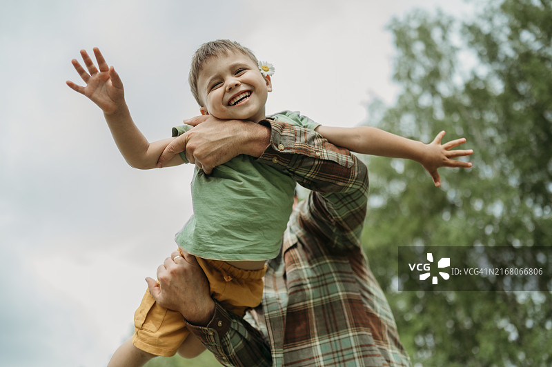 父亲扛着张开双臂的快乐儿子图片素材
