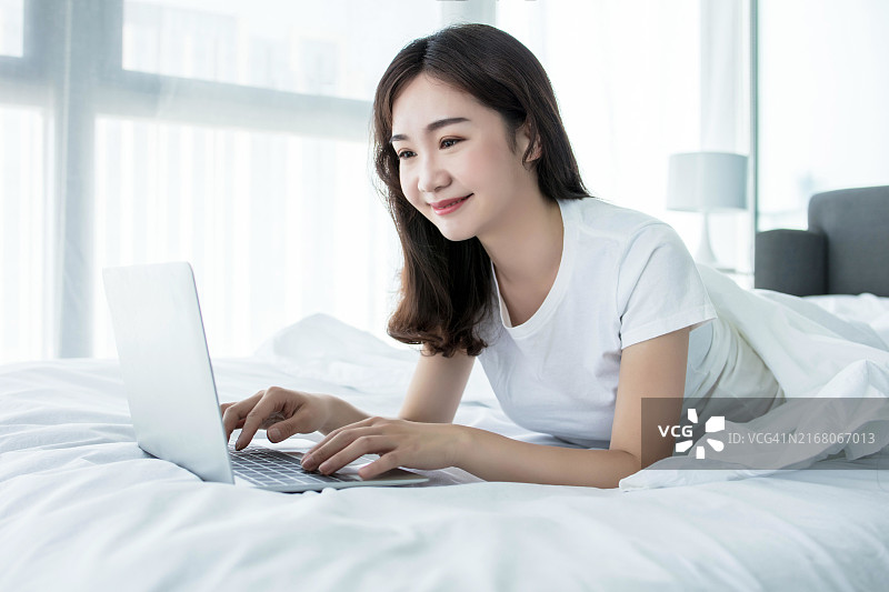 亚洲女人在床上使用笔记本电脑图片素材