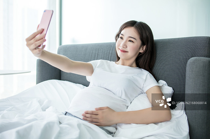 孕妇在床上幸福自拍微笑图片素材