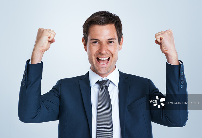 快乐的商人肖像，在白色工作室背景中，握拳庆祝晋升。兴奋的男人、赢家或年轻员工面带微笑，庆祝胜利、成功或成就图片素材