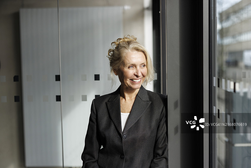 快乐的女商人眺望办公室窗外图片素材