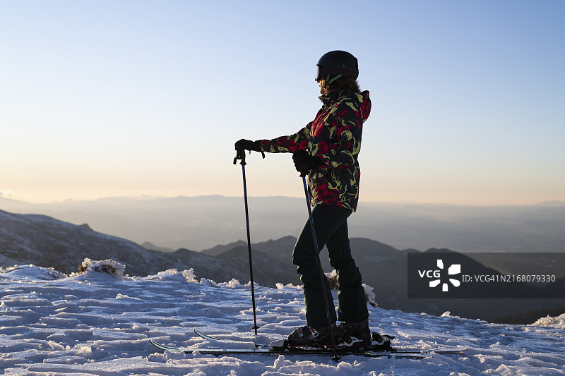 穿着保暖服装，在晴朗天空下滑雪杖的女人图片素材
