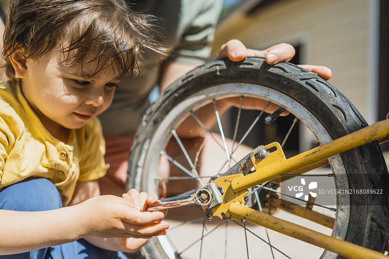儿子在后院用扳手紧固自行车轮图片素材
